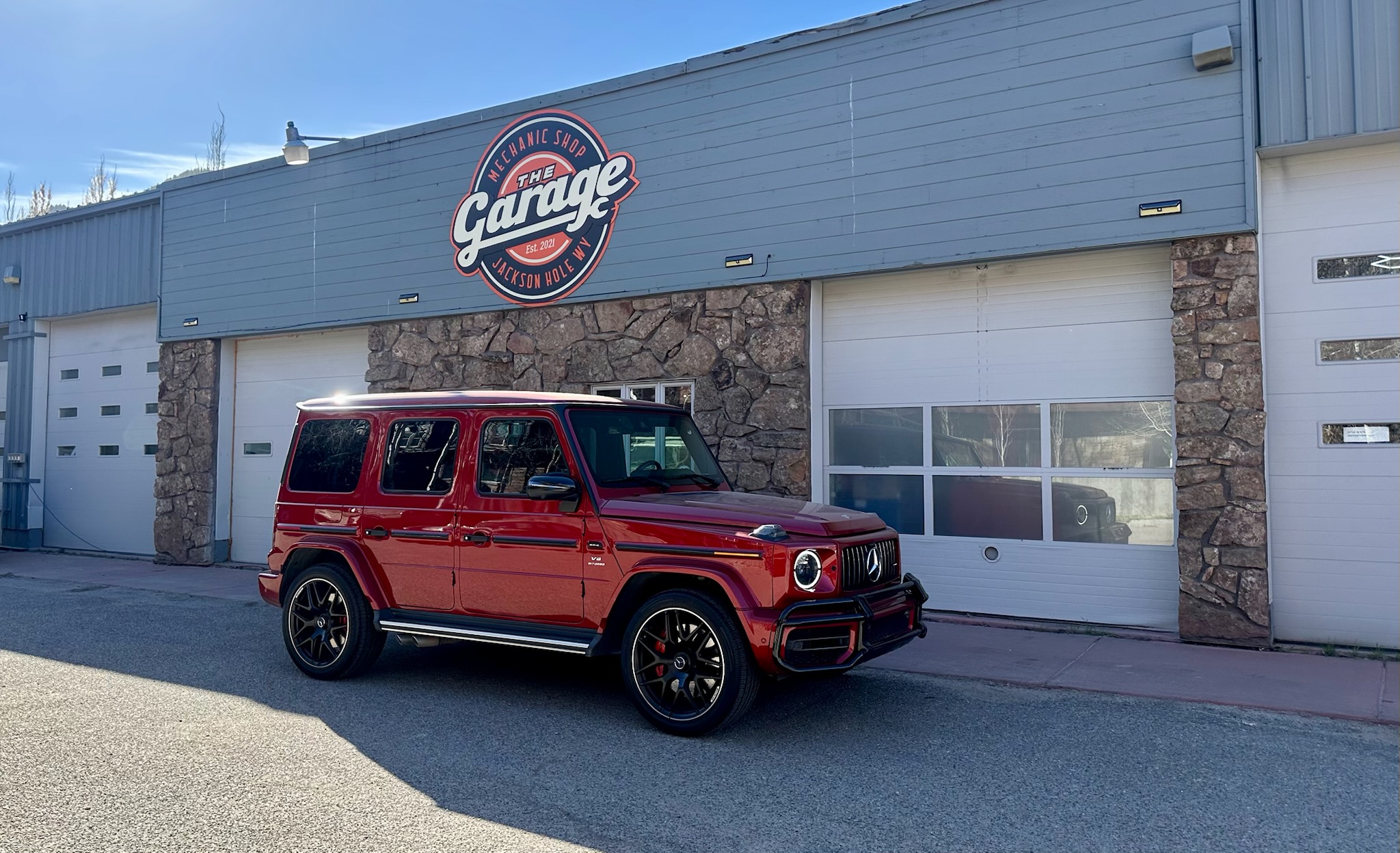 Exterior of The Garage Jackson Hole with branded sign and red Mercedes SUV parked outside