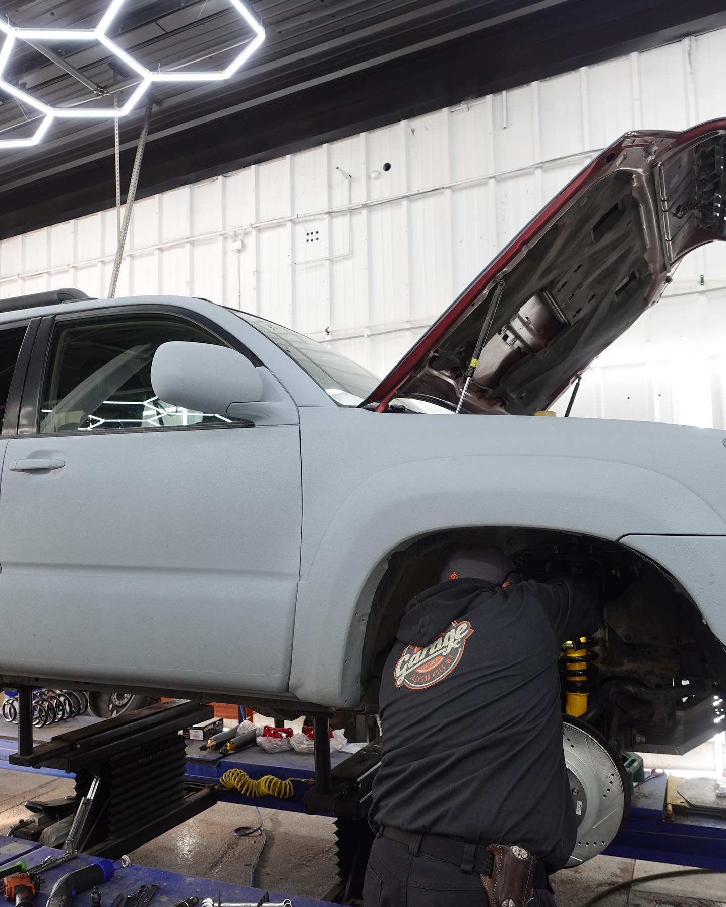 The Garage technician performing suspension and brake work on a lifted SUV